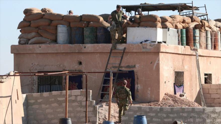Un combatiente estadounidense desciende por una escalera desde una barricada en el norte de la ciudad siria de Al-Raqa, 6 de noviembre de 2016.