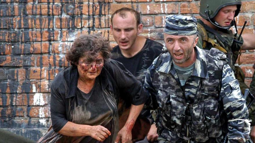 Un soldado ruso ayuda a una mujer herida durante la operación del rescate de la escuela de Beslán, una ciudad de Ossetia del Norte, 3 de septiembre de 2004.