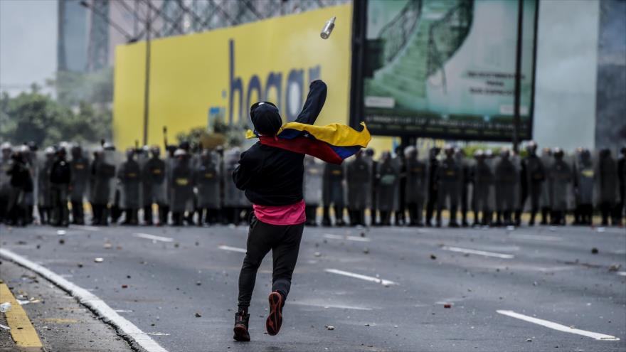 Un manifestante venezolano, que protesta contra el Gobierno del presidente Nicolás Maduro, arroja una botella contra la policía antidisturbios en Caracas, 10 de abril de 2017.