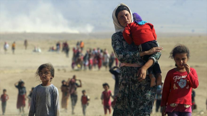 Desplazados de la minoría kurda izadí, huyen de la violencia de los terroristas del EIIL (Daesh, en árabe) en la ciudad de Sinyar, y caminan hacia la frontera siria cerca de la ciudad fronteriza siria de Elierbe, de la provincia de Al-Hasaka, 11 de agosto de 2014.