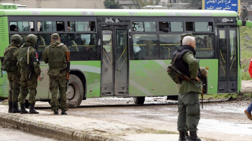 Miembros de la policía militar rusa y soldados sirios hacen guardia a las afueras del barrio de Waer, en la ciudad central de Homs, 18 de marzo de 2017.