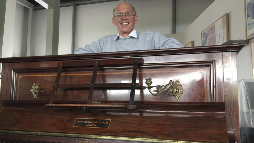 El afinador británico Martin Backhouse, posa con el piano donde encontró un tesoro de monedas de oro, en el Museo Ludlow, el Reino Unido, 20 de abril de 2017.