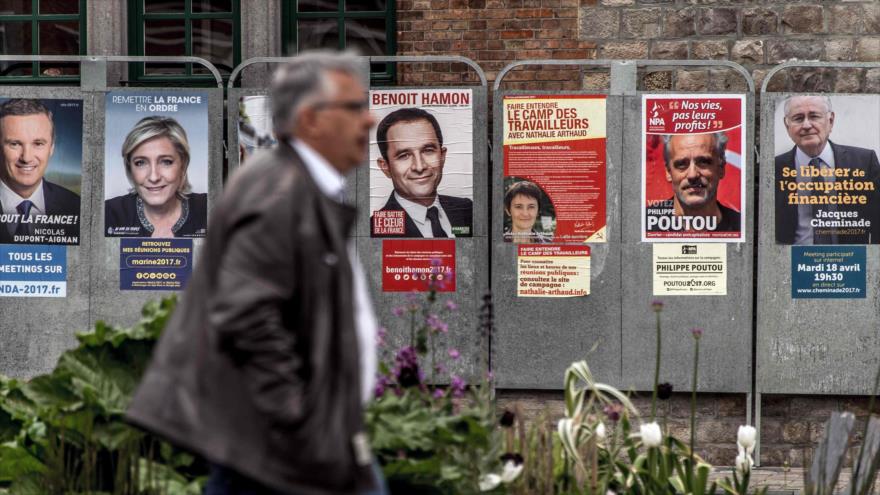 Un hombre camina frente a pancartas de los candidatos a las elecciones presidenciales de Francia en la ciudad de Bailleul, en el norte de Francia, 21 de abril de 2017.