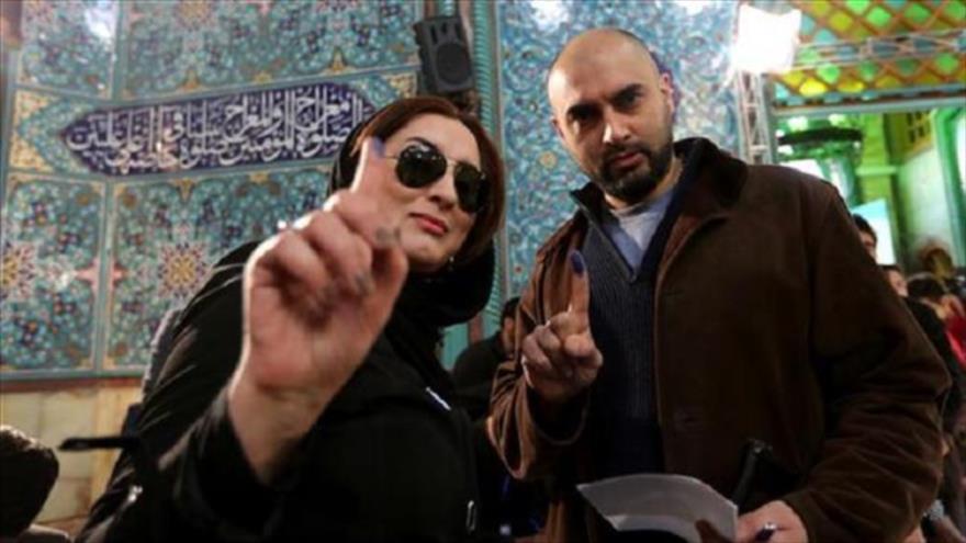 Dos iraníes gesticulan después de emitir sus votos.