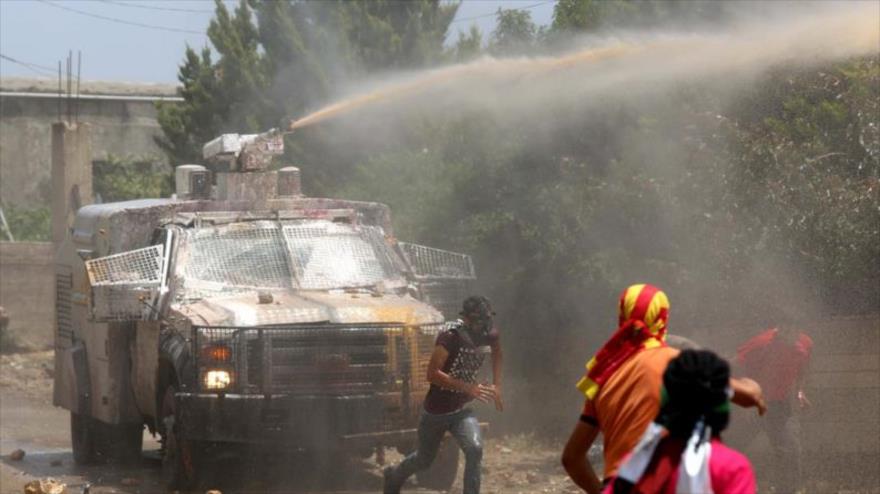 Un vehículo militar del ejército israelí emplea bombas fétidas contra los manifestantes palestinos.