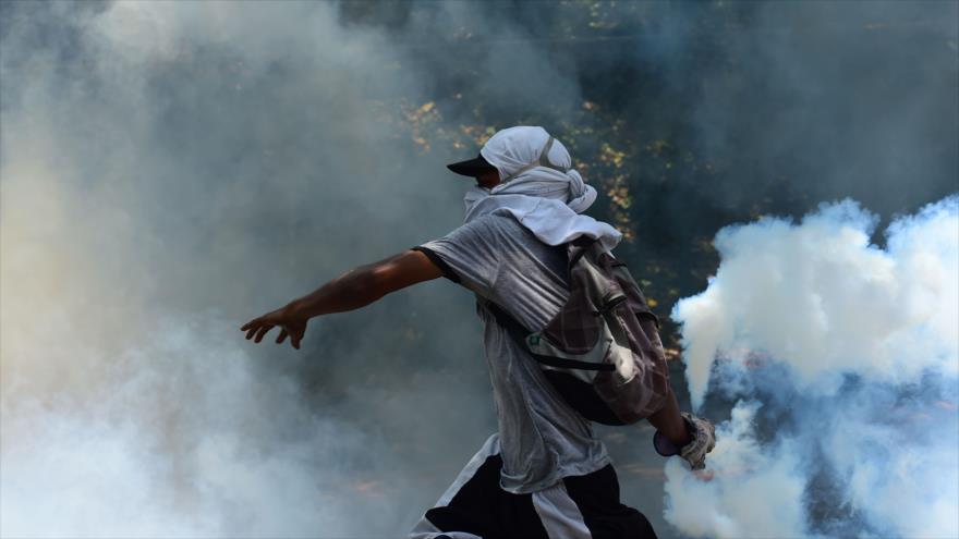 Un estudiante universitario venezolano lanza gas lacrimógeno durante una protesta antigubernamental en Caracas, capital, 4 de mayo de 2017.