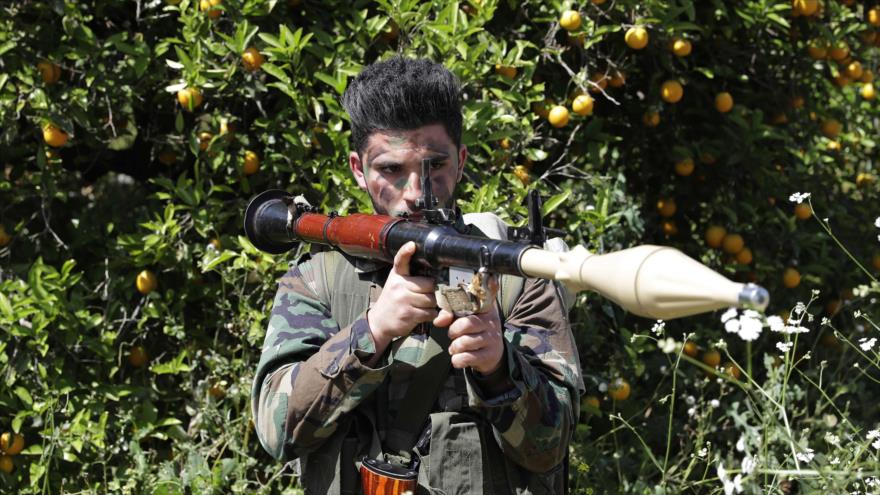 Combatiente de Hezbolá apunta con su arma en un campo de naranja cerca de la ciudad de Naqura en la frontera con los territorios palestinos ocupados, 20 de abril de 2017.