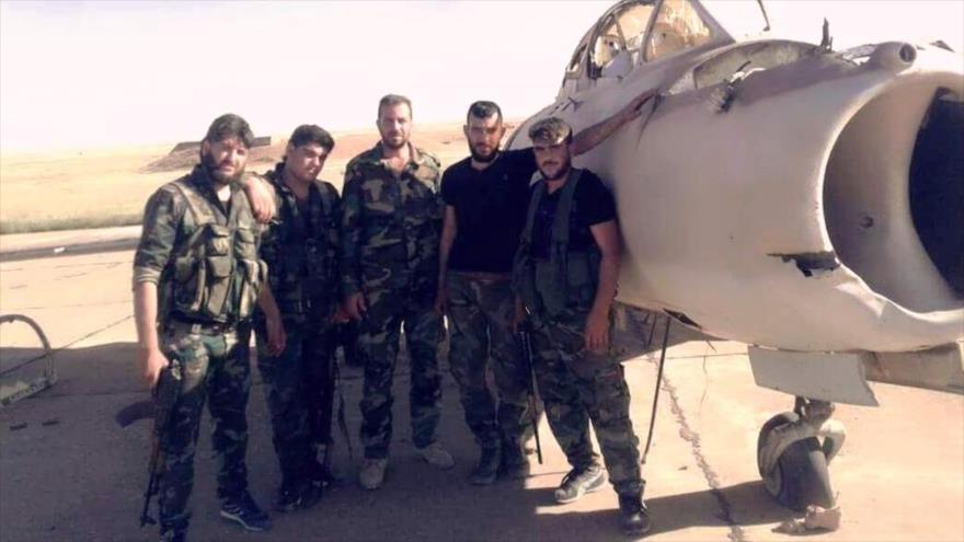 Integrantes del Ejército sirio posan junto a un destruido avión de guerra en la base aérea de Yirah, 12 de mayo de 2017.