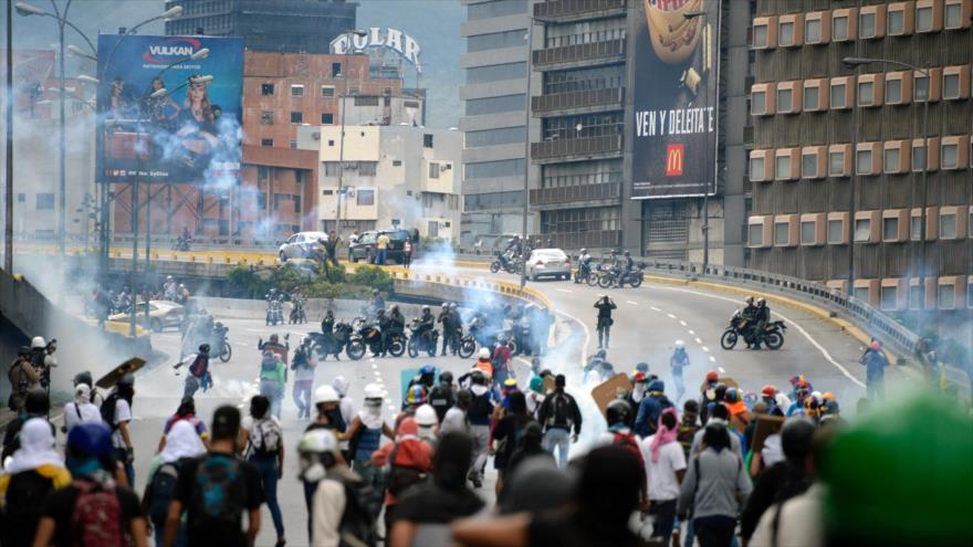 Opositores venezolanos se enfrentan con las fuerzas de seguridad en una carretera en Caracas (capital), 13 de mayo de 2017.