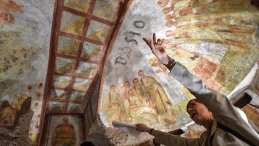 Un experto señala frescos recién restaurados en el techo de una cripta subterránea en las catacumbas de San Domitila en Roma.