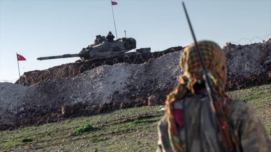 Un combatiente kurdo de las Unidades de Protección Popular (YPG, en kurdo) porta su arma cerca de un tanque turco, en Alepo (norte de Siria), febrero de 2015.