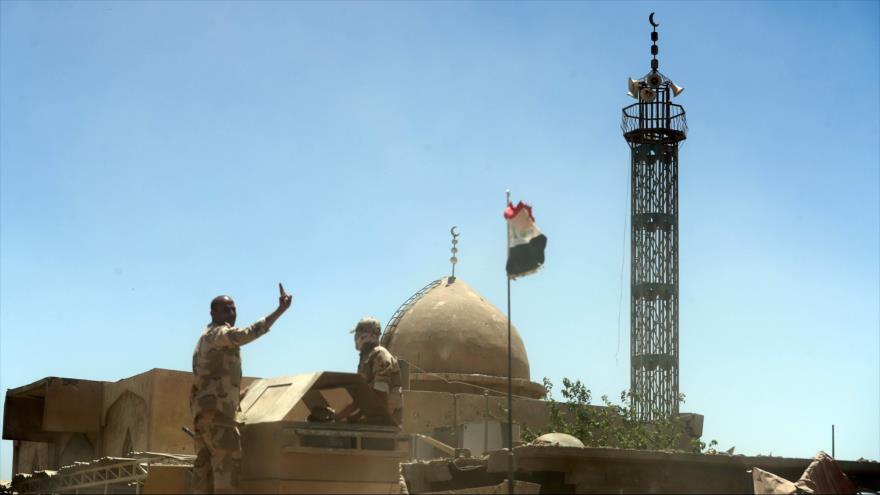 Soldados iraquíes enarbolan su bandera mientras avanzan por el oeste de Mosul, 1 de junio de 2017.