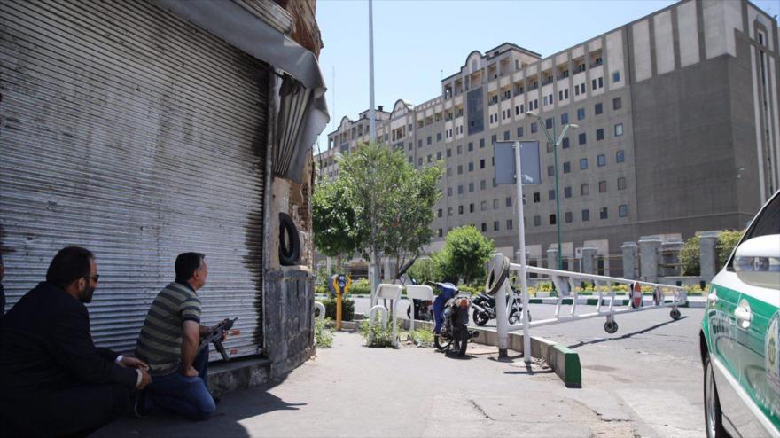 Un policía iraní encubierto (izq.) sostiene un arma fuera de la sede del Parlamento en la capital iraní, Teherán, 7 de junio de 2017.