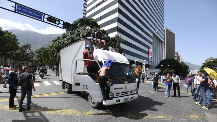 Opositores encapuchados intentan bloquear una calle en Caracas, capital venezolana, 26 de junio de 2017.