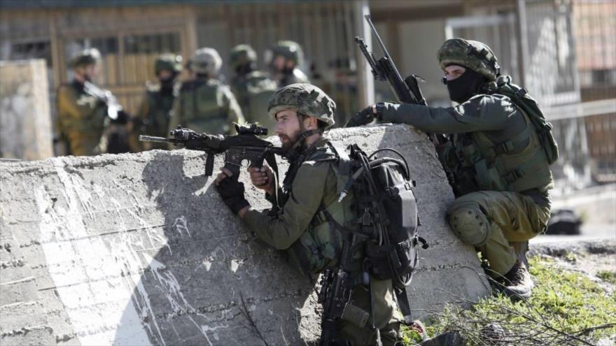 Soldados israelíes apuntan contra palestinos en una manifestación en la ocupada Cisjordania.