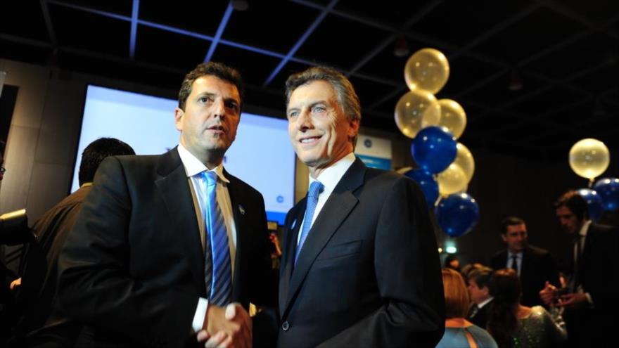 El líder de la fuerza política 1País, Sergio Massa, da la mano al presidente argentino, Mauricio Macri (dcha.).