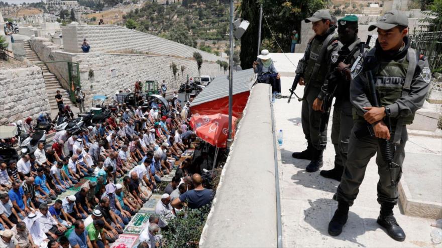 Soldados del régimen israelí observan a los fieles musulmanes palestinos rezar en la explanada de las Mezquitas en Al-Quds (Jerusalén).