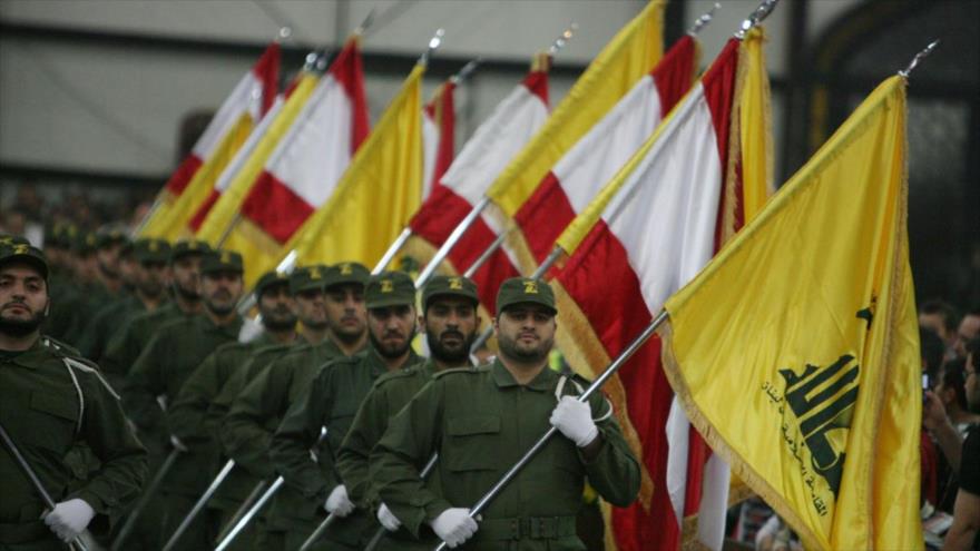 Las fuerzas de Hezbolá portan banderas de El Líbano y del movimiento libanés durante un desfile militar.