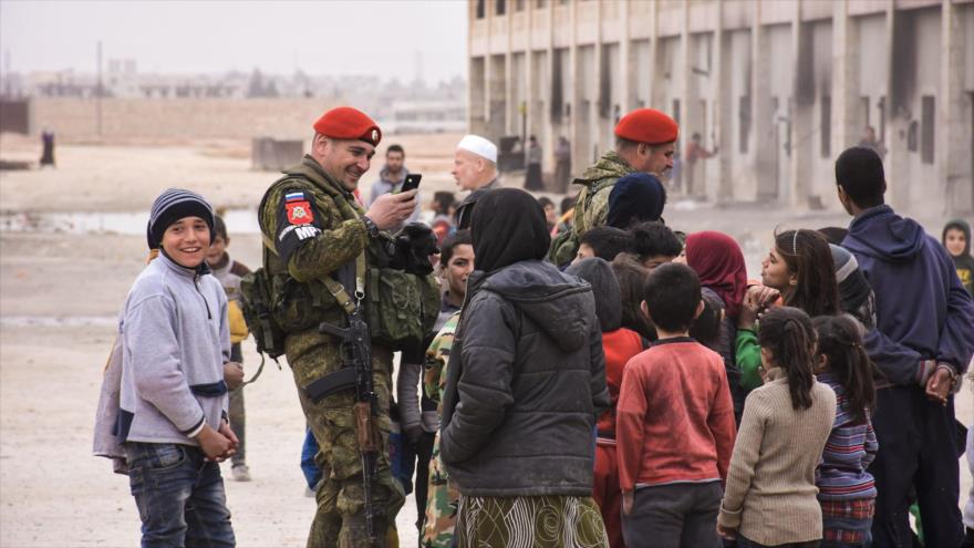 Dos agentes de la Policía Militar rusa entre los niños sirios en Alepo, norte de Siria, 1 de marzo de 2017.