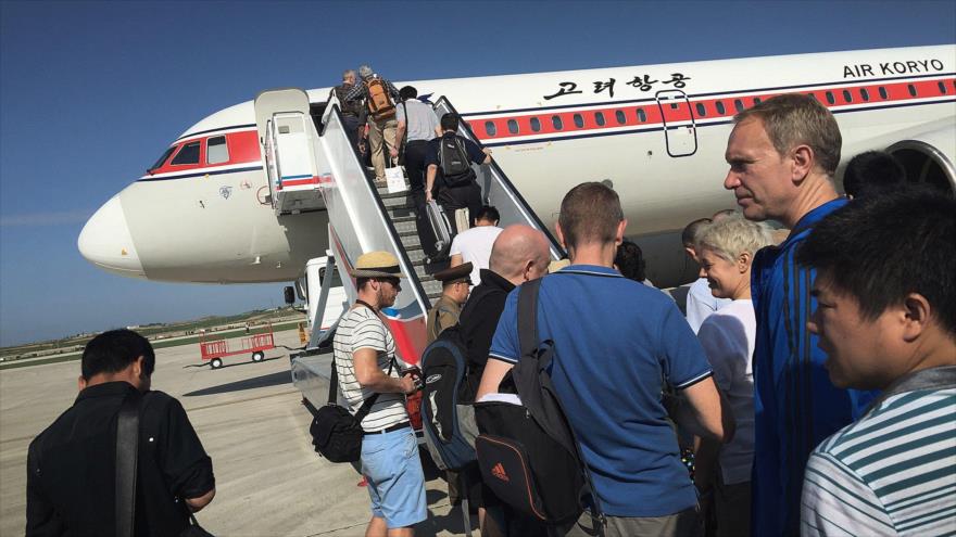 Varios turistas estadounidenses están subiendo a un avión de Air Koryo, la aerolínea oficial de Corea del Norte.