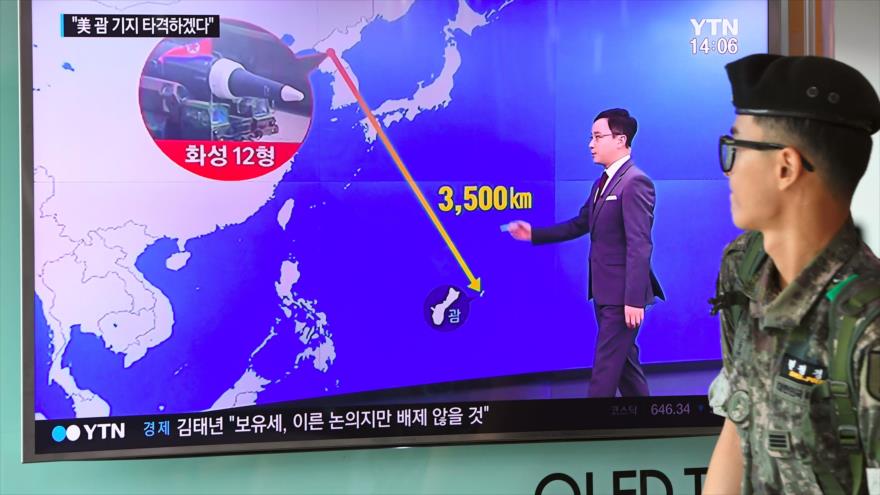 Un soldado surcoreano pasa por una pantalla de televisión que muestra un gráfico de la distancia entre Corea del Norte y Guam en una estación de tren en Seúl, 9 de agosto de 2017.