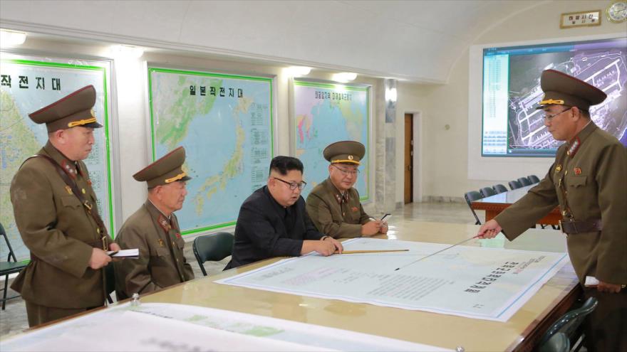 El líder norcoreano, Kim Jong-un, mira el mapa de ataque a la isla estadounidense de Guam, en una reunión con sus más altos comandantes.