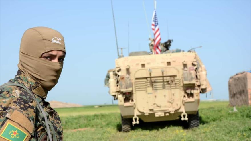 Un efectivo kurdo, de pie cerca de un vehículo blindado estadounidense en la aldea norteña siria de Darbasiyah, zona fronteriza con Turquía.