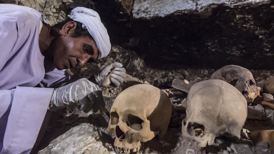 Un arqueólogo egipcio desentierra cráneos y restos de huesos en una tumba antigua descubierta en la necrópolis de Dra Abu el-Naga, 9 de septiembre de 2017.
