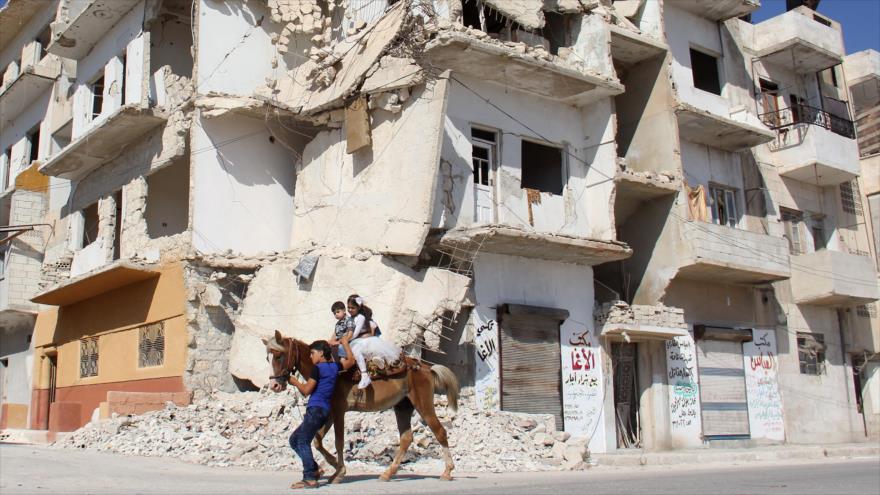 Niños sirios montan a caballo por una calle dañada en la ciudad de Idlib (noroeste de Siria), 1 de septiembre de 2017.