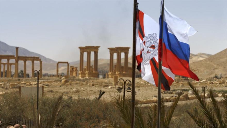 Una bandera de Rusia (dcha.) y otra del Centro ruso Internacional de Acción contra las Minas, izadas en la ciudad siria de Palmira.