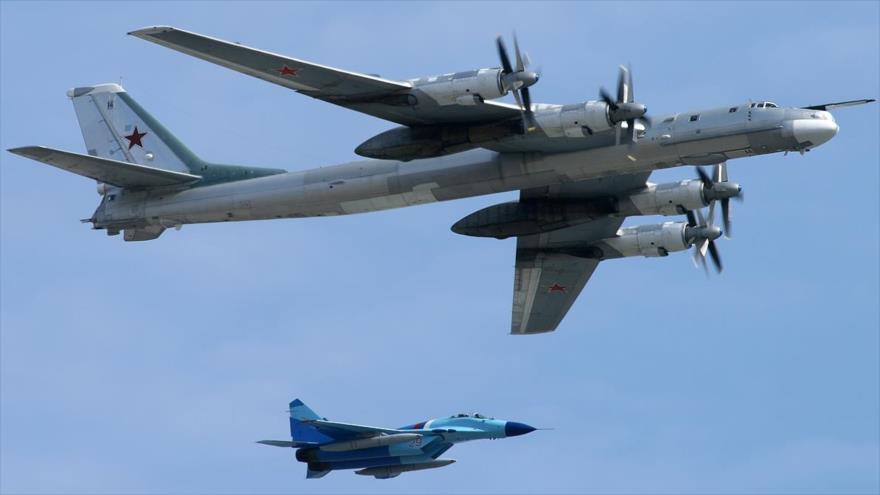 Un bombardero estratégico TU-95MS acompañado por un caza SU-35 de la Fuerza Aérea de Rusia.