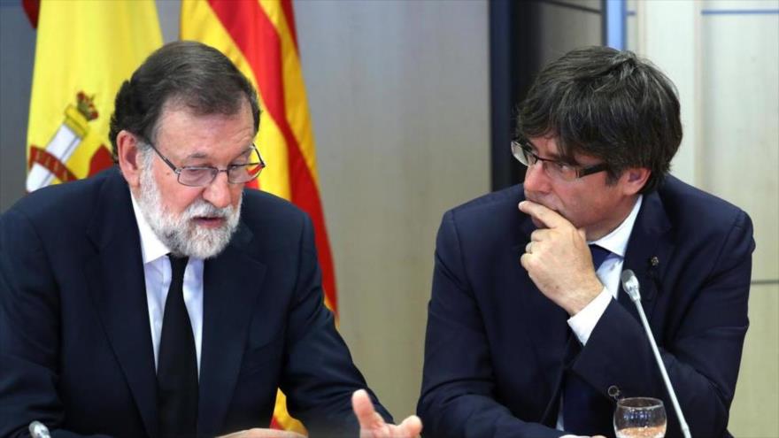 El presidente del Gobierno español, Mariano Rajoy (izda.), y el presidente de Generalitat, Carles Puigdemont, hablan en la reunión del gabinete de crisis.