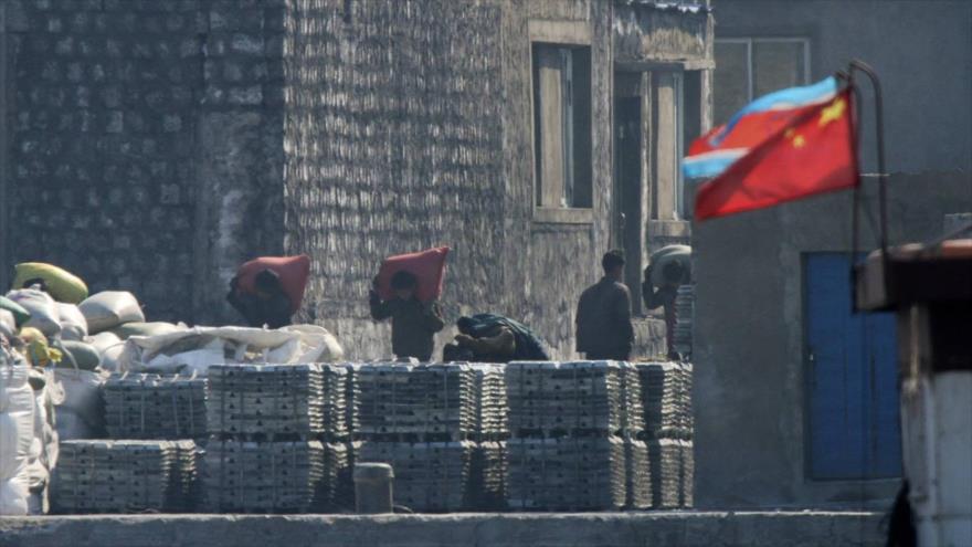 Norcoreanos cargan sacos en un astillero de Sinuiju. Del otro lado, la localidad china de Dandong. 