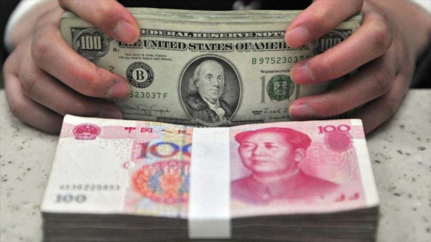 Una persona contando billetes de yuanes junto con dólares estadounidenses.