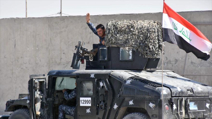 Un combatiente de la Policía Federal iza la bandera iraquí en una carretera cerca de Erbil (capital del Kurdistán iraquí), 20 de octubre de 2017.