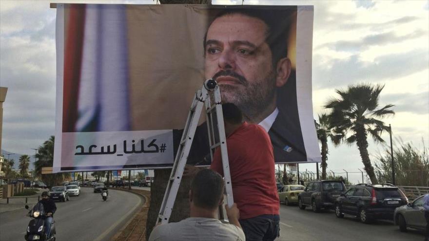 Los trabajadores cuelgan un póster del ex primer ministro libanés Saad Hariri en una calle en Beirut, capital de El Líbano, 9 de noviembre de 2017.