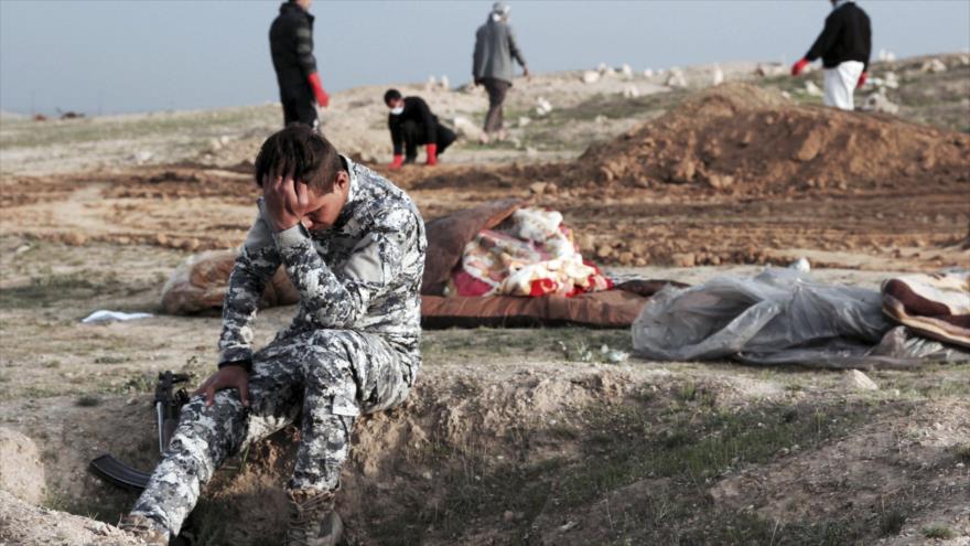 Agente de la policía iraquí reacciona al ver los cadáveres de una fosa común en el norte de Irak.