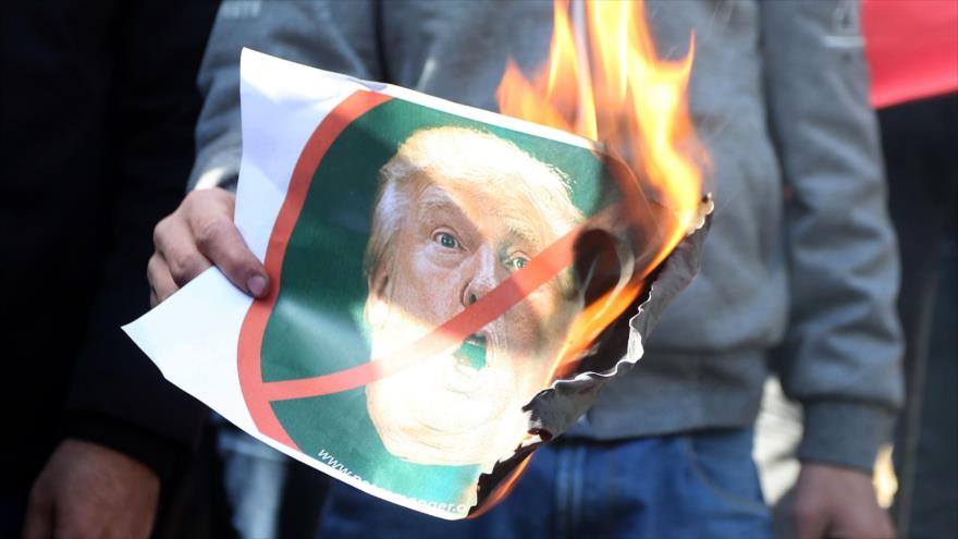 Un palestino quema una imagen del presidente de EE.UU., Donald Trump, durante una protesta en la Cisjordania ocupada, 7 de diciembre de 2017.