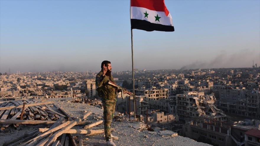 Un soldado sirio junto a una bandera nacional en Alepo (noroeste).