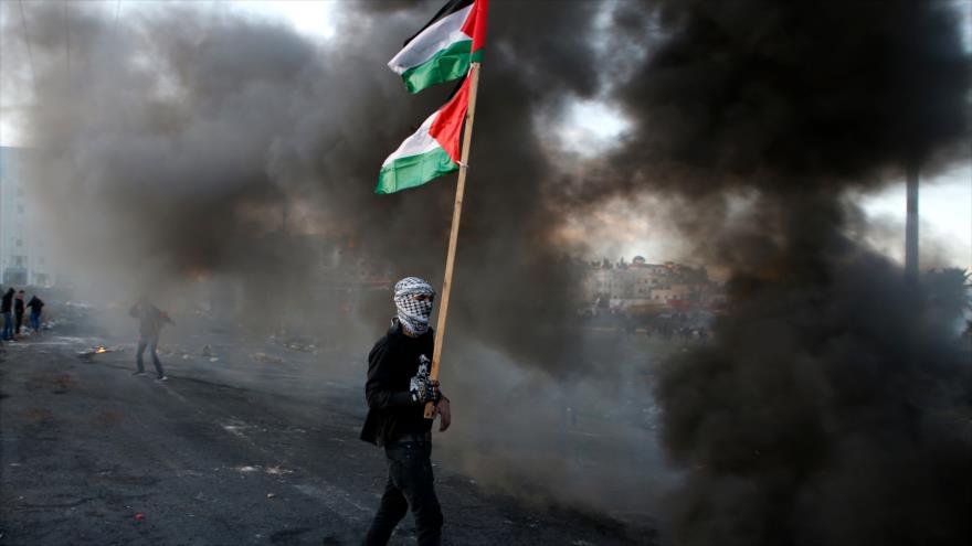 Un hombre lleva la bandera palestina durante una manifestación cerca de un puesto de control israelí en Ramalá, 9 de diciembre de 2017.