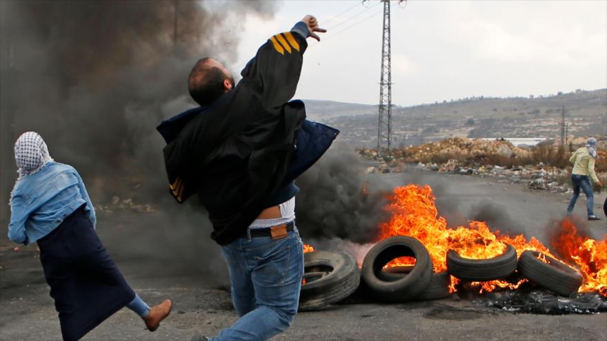 Palestinos lanzan piedras contra fuerzas israelíes durante protestas en la ciudad cisjordana de Ramalá, 13 de diciembre de 2017.