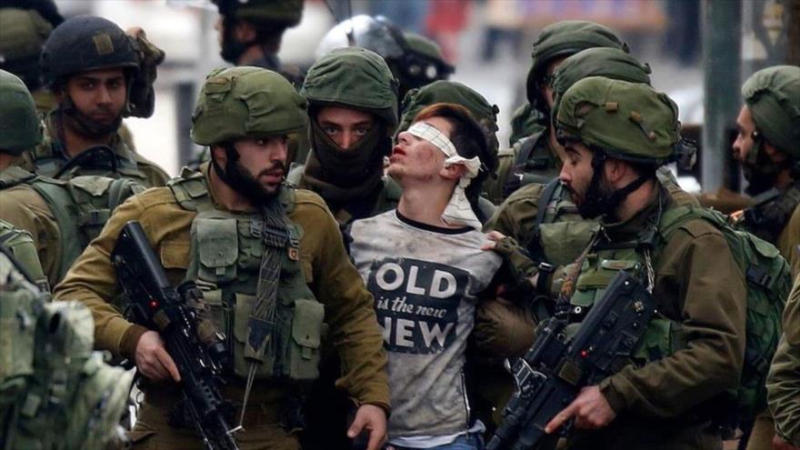 Soldados israelíes detienen a un menor palestino.