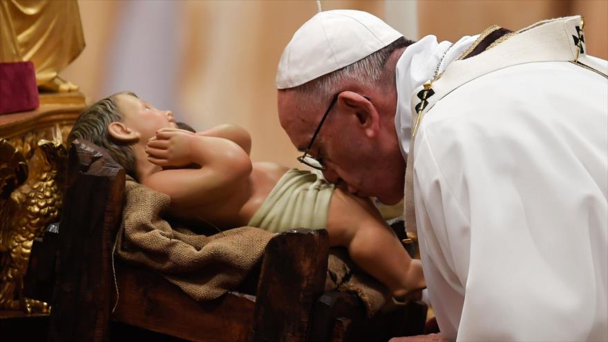 El Papa Francisco besa una estatua del niño Jesús en una misa en Nochebuena, 24 de diciembre de 2017.