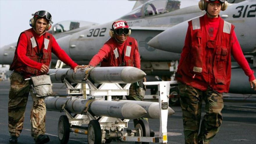 Militares transportan misiles AIM-120 AMRAAM en la cubierta del portaviones USS Kitty Hawk.