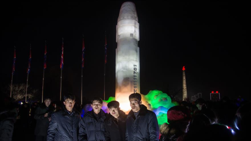 Un grupo de norcoreanos frente a una escultura de hielo que representa un misil balístico intercontinental Hwasong-15 en Pyongyang, la capital, 31 de diciembre de 2017.
