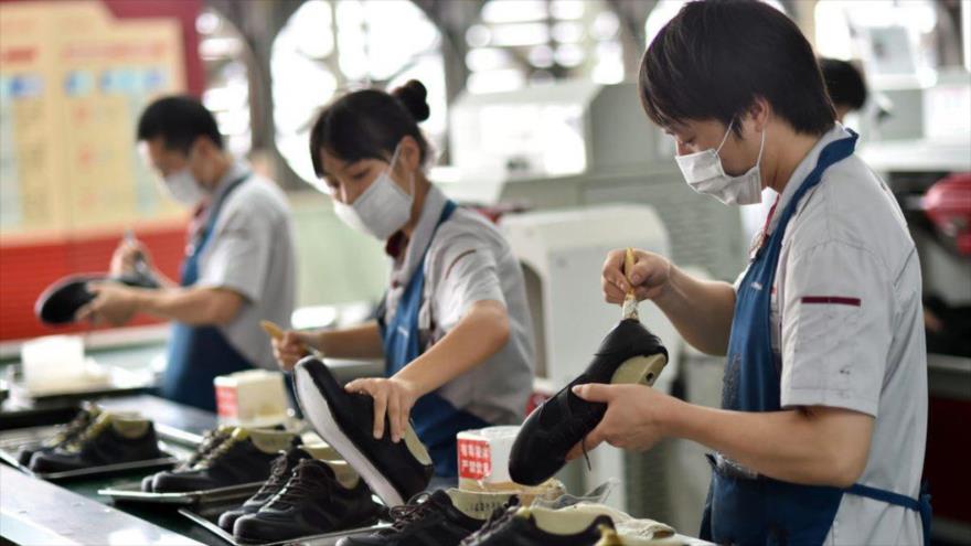 Trabajadores chinos fabricando zapatos en una fabrica local.