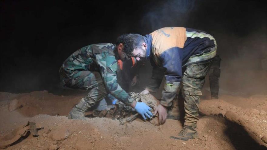 Fuerzas sirias sacan cuerpos de las víctimas civiles sirios en una fosa común en la ciudad de Al-Raqa.