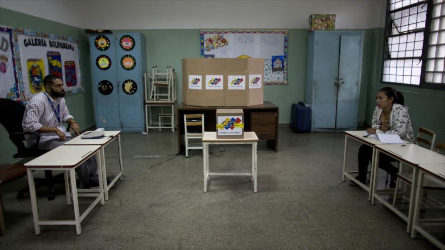 Funcionarios venezolanos esperan a los votantes en una mesa electoral durante las elecciones en Caracas (capital).