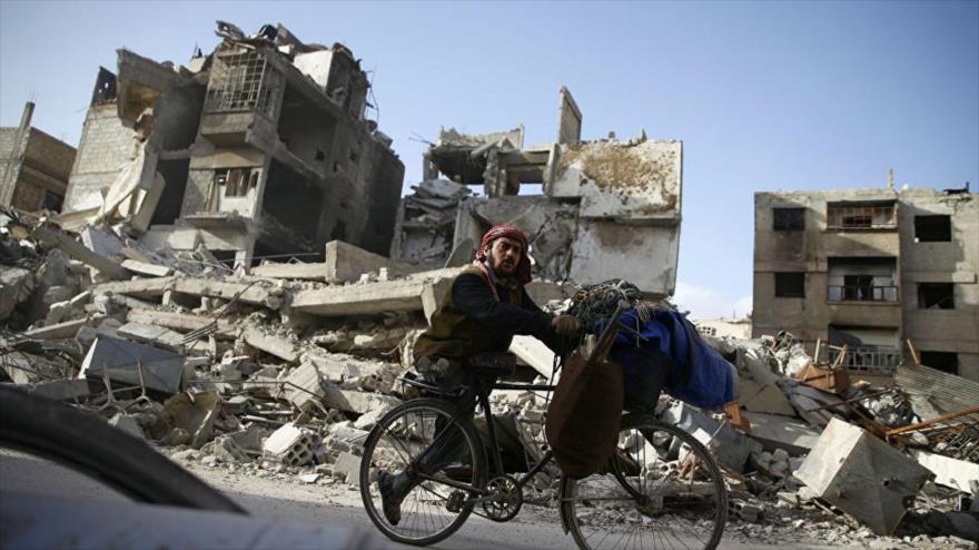 Un civil sirio pasa ante los escombros generados por la guerra en la región de Guta Oriental.