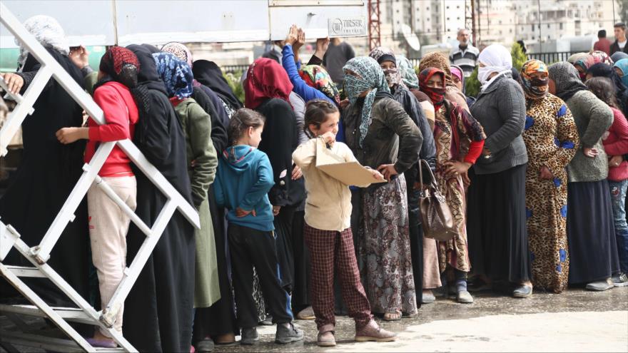 Decenas de civiles hacen cola para recibir ayuda humanitaria de las oenegés, en Afrin, noroeste de Siria, 22 de marzo de 2018.